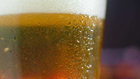 Macro-shot-of-a-beer-glass-with-cold-beer-bubbles-rise-in-the-glass.-Slow-motion-beer-bubbles